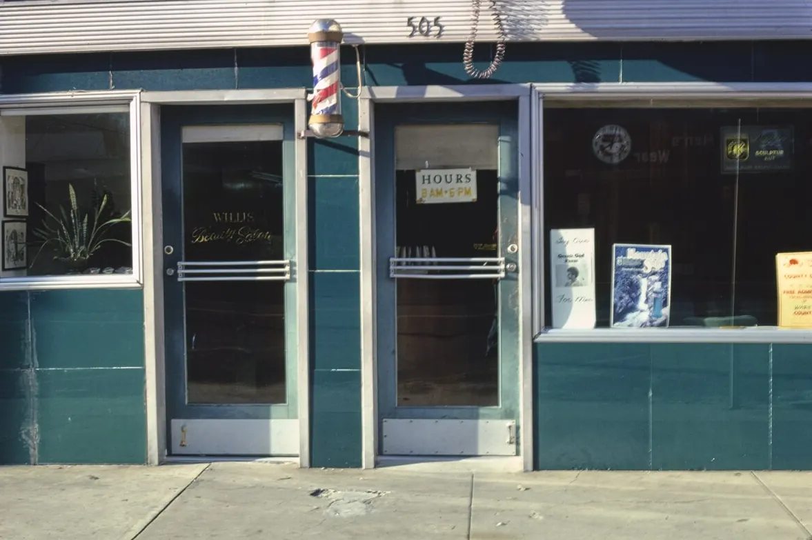 A teal beauty shop front with a barber pole