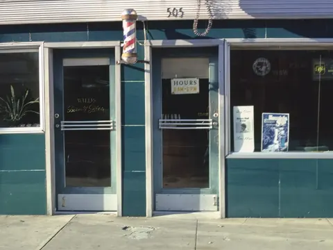 A teal beauty shop front with a barber pole