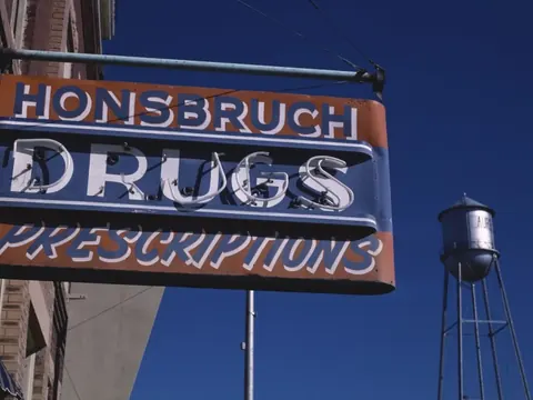 A neon drugstore sign reading “Drugs, Prescriptions”